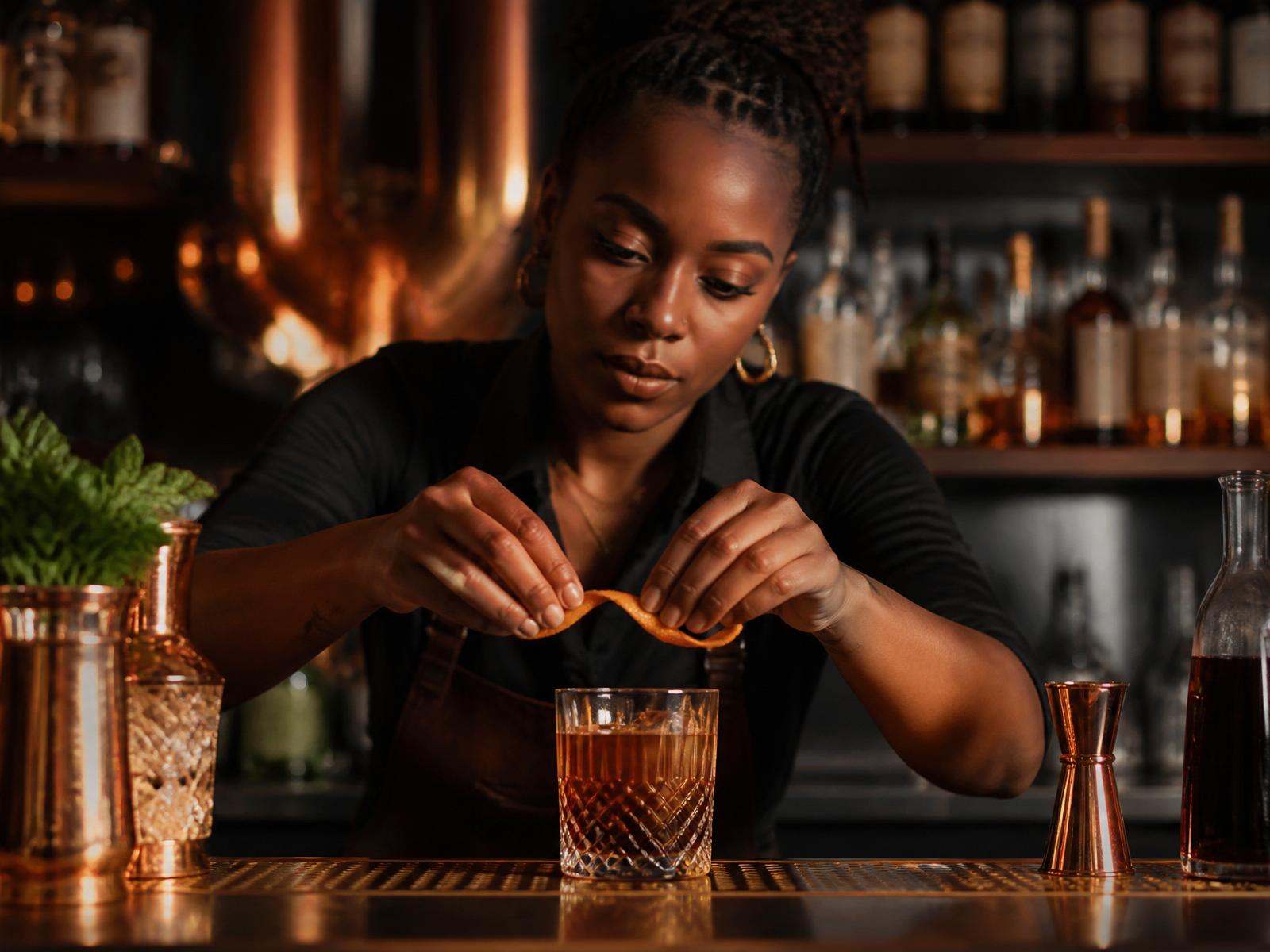 African American bartender garnishing a craft cocktail with a citrus twist in an upscale lounge